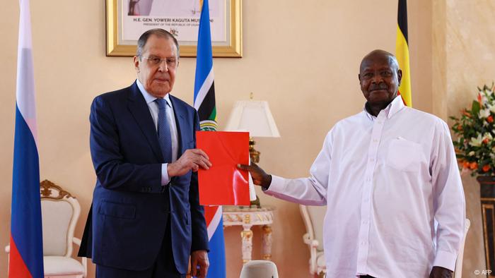 Sergey Lavrov and Yoweri Museveni hold up a red folder between them