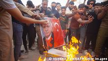 Protesters burn the portrait of the Turkish President during a demonstration condemning the artillery bombardment of a Kurdish hill village, which Iraq blames on neighbouring Turkey, outside the Turkish consulate in the southern Iraqi city of Basra on July 21, 2022. - An angry and grieving Iraq buried nine holidaymakers, including a newlywed, killed in the artillery bombardment of a Kurdish hill village. Baghdad blames neighbouring Turkey and summoned the Turkish ambassador in protest. Ankara denied its troops were responsible and instead accused rebels of the outlawed Kurdistan Workers Party (PKK). Germany, France and Iran condemned the attack. (Photo by Hussein FALEH / AFP) (Photo by HUSSEIN FALEH/AFP via Getty Images)