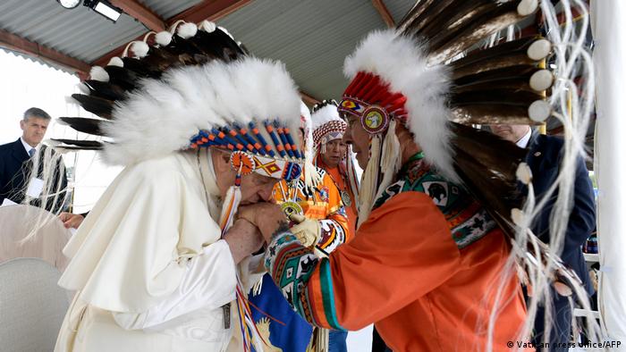 This handout picture taken and released on July 25, 2022 by the Vatican press office shows Pope Francis (L) wearing a headdress presented to him by Indigenous leaders at Muskwa Park in Maskwacis, south of Edmonton, western Canada, on July 25, 2022.