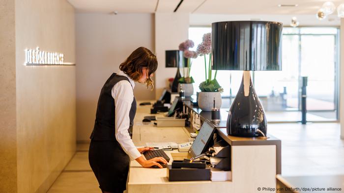 A hotel receptionist looks at a computer screen. A hotel receptionist looks at a computer screen.