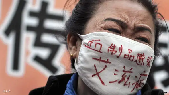 A hemophiliac wearing a face mask bearing the words Blood products infect us with AIDS cries while she with others take center stage during an AIDS awareness event on the World AIDS Day held at the Beijing's south railway station, Tuesday, Dec. 1, 2009. A group of protesters, who has infected HIV from blood transfer products including relatives of the victim disrupted a UNAIDS event, calling for greater support for people living with AIDS/HIV in China. (AP Photo/Andy Wong)