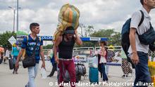 A man carries a large load on his back, with the strap around his forehead, as he works as a “lomo taxista,” or taxi of the lower back, across the border from Cucuta, Colombia to Venezuela, Friday, Sept. 20, 2019. Many Venezuelans who have little money to migrate, or prefer to stay closer to home, are settling in border towns like San Antonio, where the informal economy of black market goods and street vending provide them with some work opportunities. (AP Photo/Rafael Urdaneta)