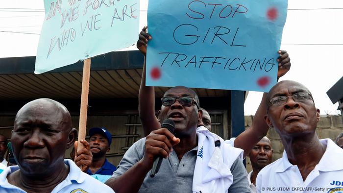 Men hold signs, one of which reads: Stop girl trafficking'