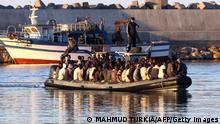 Sub-Saharan African migrants are rescued by the Libyan coastguard after their inflatable boat started to sink off the coastal town of Guarabouli, 60 kilometres east of the capital Tripoli on November 20, 2014. There were 108 people rescued from the sinking raft. Mired in unrest and political chaos, Libya has been a launchpad for illegal migrants trying to reach Europe and who turn to people smugglers to cross the Mediterranean, mainly to Italy. AFP PHOTO / MAHMUD TURKIA (Photo credit should read MAHMUD TURKIA/AFP via Getty Images)