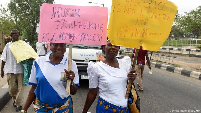 Women hold placards demonstrating against human trafficking