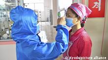 Temperature checks are conducted for workers at a factory in Pyongyang on June 10, 2022, amid fears over the spread of coronavirus infections. (Kyodo)