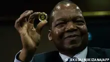 Zimbabwe Reserve Bank governor John Mangudya displays the country's new Mosi-oa-Tunya gold coin in Harare on July 25, 2022. - The new coin which weighs 1oz is meant to stabilise the country's currency against a resurgent inflation. (Photo by Jekesai NJIKIZANA / AFP)