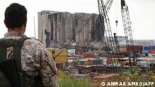 A Lebanese security officer looks at the heavily damaged grain silos at the port of the Lebanese capital Beirut, on July 31, 2022, following a partial collapse due to an ongoing fire since the beginning of the month. (Photo by Anwar AMRO / AFP)