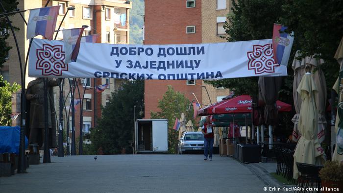 Serbische Flaggen und ein Spruchbanner über einer Straße in einem Wohngebiet