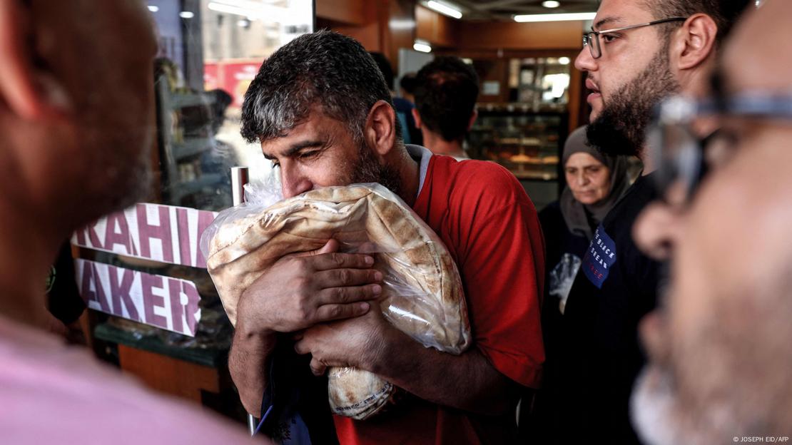 A man walks out of a bakery clutching a bag of subsidised flatbread