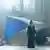 Serienausschnitt: Ein Mann mit langer Maske steht vor einer Treppe und trägt ein langes schwarzes Gewand.