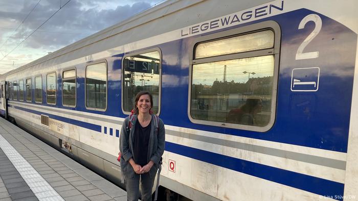 DW reporter Lisa Stuve stands on the platform in front of an overnight train.