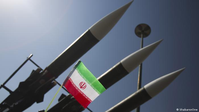 Three missiles with Iran's flag hanging in front of them