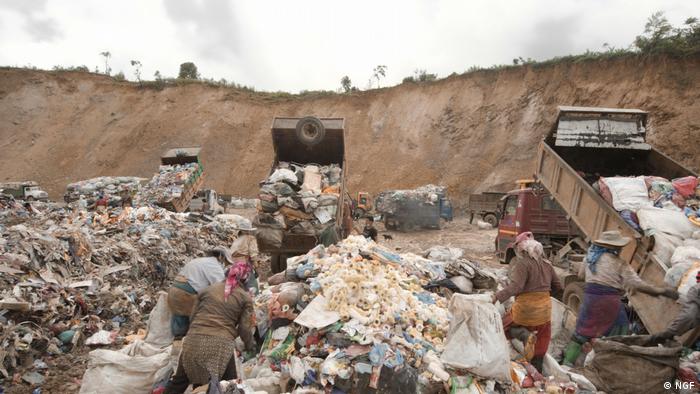 Eine große Grube, in der Menschen LKWs mit Müll beladen.