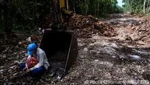 A woman activist sits on the shovel bucket of a piece of heavy machinery to stop it from being used in a construction zone