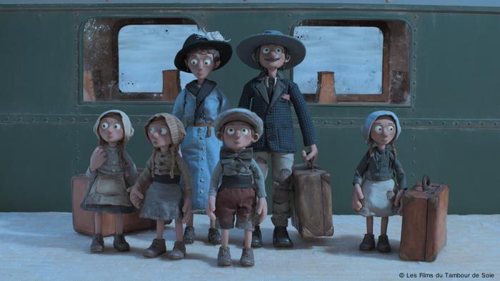 Zwei Erwachsene und vier Kinder, durch animierte Figuren dargestellt, stehen mit Koffern ab einem Bahnsteig und sehen sich um.