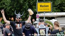 Festival-Besucher posieren vor dem Ortseingangsschild. Nach pandemiebedingter Pause findet vom 4. bis 6. August 2022 wieder das Heavy-Metal-Festival Wacken Open Air in Schleswig-Holstein statt. +++ dpa-Bildfunk +++