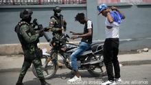 Armed forces check two men who were riding a motorcycle for weapons, at the area of ​​state offices of Port-au-Prince, Haiti, Monday, July 11, 2022. Radio TV Caraibe, a popular radio station in Haiti announced on Monday that it would stop broadcasting for one week to protest widespread violence in the capital. (AP Photo/Odelyn Joseph)