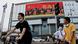 A large screen on a building showing promotion for the Chinese People's Liberation Army (PLA) is seen past cyclists in Beijing A large screen on a building showing promotion for the Chinese People's Liberation Army (PLA) is seen past cyclists in Beijing