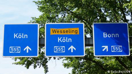 Three blue overhead autobahn signs, reading 555, Köln, Wesseling - Köln and Bonn.