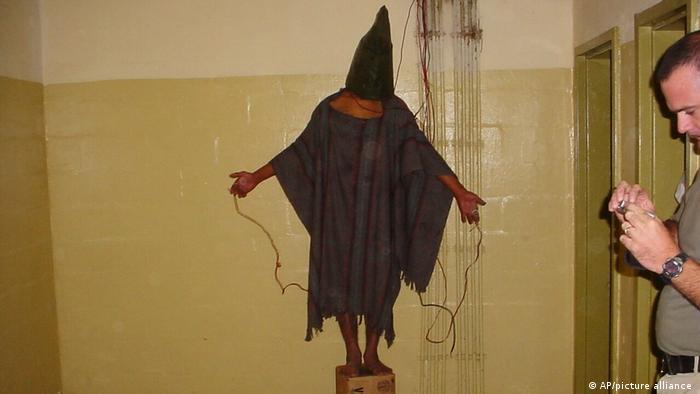 Ein Häftling steht Ende 2003 im Abu-Ghraib-Gefängnis in Bagdad auf einer Kiste, trägt Sack über dem Kopf trägt und ist mit Drähten verbunden