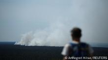 A man watches as smoke rises up above the Grunewald forest due to an explosion in a munitions depot in the Grunewald forest in Berlin, Germany August 4, 2022. REUTERS/Annegret Hilse