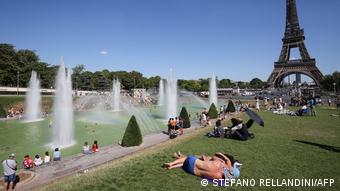 People in the sun at the Trocadero fountain, with the Eiffel Tower in background, on a sunny summer afternoon in Paris, on August 3