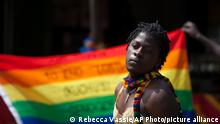 A transgender Ugandan poses in front of a rainbow flag during the 3rd Annual Lesbian, Gay, Bisexual and Transgender (LGBT) Pride celebrations in Entebbe, Uganda, Saturday, Aug. 9, 2014. Scores of Ugandan homosexuals and their supporters are holding a gay pride parade on a beach in the lakeside town of Entebbe. The parade is their first public event since a Ugandan court invalidated an anti-gay law that was widely condemned by some Western governments and rights watchdogs. (AP Photo/Rebecca Vassie)