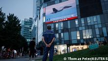 A man watches a CCTV news broadcast, showing a fighter jet during joint military operations near Taiwan by the Chinese People's Liberation Army's (PLA) Eastern Theatre Command, at a shopping center in Beijing, China, August 3, 2022. REUTERS/Thomas Peter