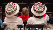 Zwei Frauen tragen Hüte in Form von Schwarzwälder Kirschtorten (Quelle: Christoph Schmidt/dpa/picture alliance)