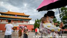 A woman holding a baby walks out of the Forbidden City in Beijing on September 1, 2020. (Photo by WANG Zhao / AFP) (Photo by WANG ZHAO/AFP via Getty Images)