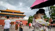 A woman holding a baby walks out of the Forbidden City in Beijing on September 1, 2020. (Photo by WANG Zhao / AFP) (Photo by WANG ZHAO/AFP via Getty Images)