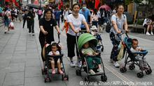 People push baby strollers along a business street in Beijing on July 13, 2021. (Photo by WANG Zhao / AFP) (Photo by WANG ZHAO/AFP via Getty Images)