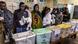 A group of voters queue while waiting to vote in front on ballot boxes at a polling station A group of voters queue while waiting to vote in front on ballot boxes at a polling station