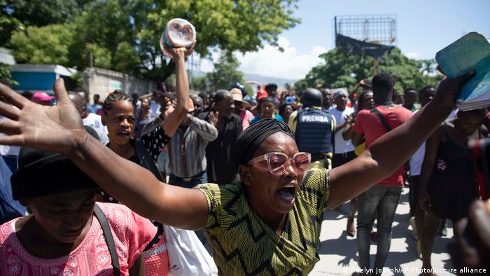 A woman in a crowd protesting gang violence.