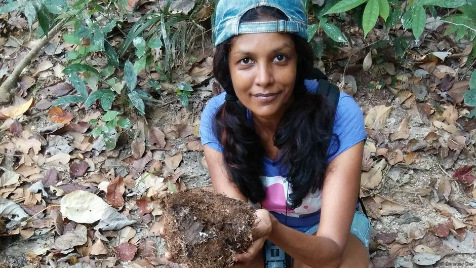 Christine Das wearing a baseball cap and holding elephant dung at the Ulu Muda Forest Reserve