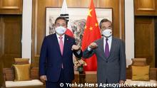 In this photo provided by South Korea Foreign Ministry, South Korean Foreign Minister Park Jin, left, bumps elbows with his Chinese counterpart Wang Yi prior to their meeting in Qingdao, China, Tuesday, Aug. 9, 2022. (South Korea Foreign Ministry via AP)