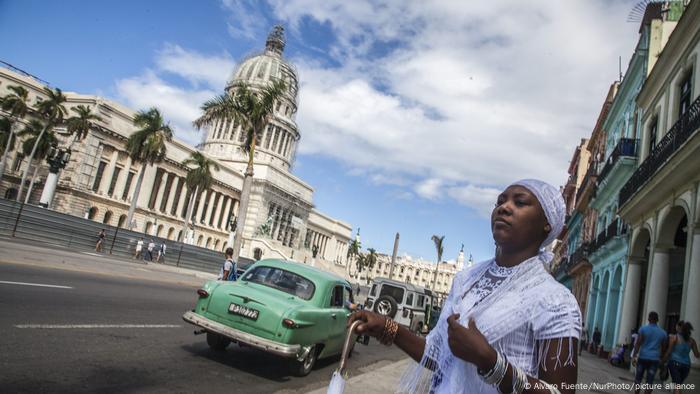 Straßenszene in Havanna, eine Frau steht am Straßenrand, im Hintergrund das Capitol 