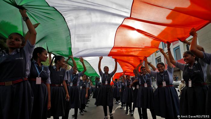 Schulkinder in Schuluniform tragen eine riesige indische Flagge durch die Straße