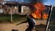 A man holding a machete reacts next to a fire after community members burned shacks and belongings A man holding a machete reacts next to a fire after community members burned shacks and belongings