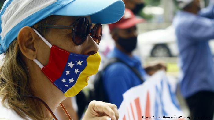 Una mujer con gafas y mascarilla de la bandera de Venezuela particpa en una protesta.