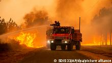 A fire officer douses flames from a fire truck in the Gironde region of France