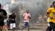 Protesters running through the streets of Freetown, with dark smoke in the background Protesters running through the streets of Freetown, with dark smoke in the background