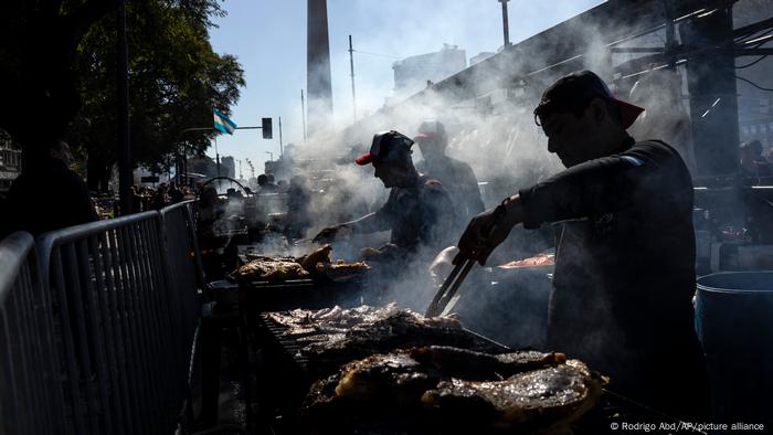 Argentina: asadores retratados a contraluz durante el IV Campeonato Federal del Asado, en la avenida 9 de julio, en Buenos Aires. De fondo: el Obelisco, un símbolo de la ciudad.