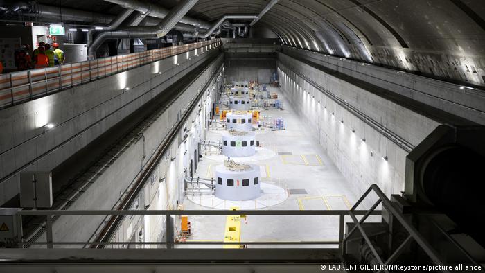 Das Bild zeigt die unterirdische Kammer des Kraftwerks, in der sich, hintereinander aufgereiht, die sechs weißen Turbinen befinden.