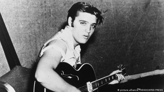 Elvis Presley in jungen Jahren an der Gitarre, schwarzweiß-Foto.