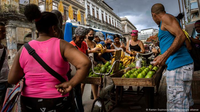 People buy fruit and vegetables at a mobile stand on a street in Havana