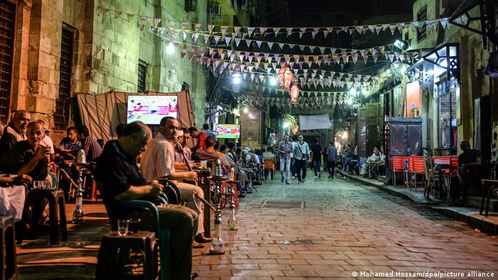 Late night street scene with people smoking shisha and street lights in Egypt 