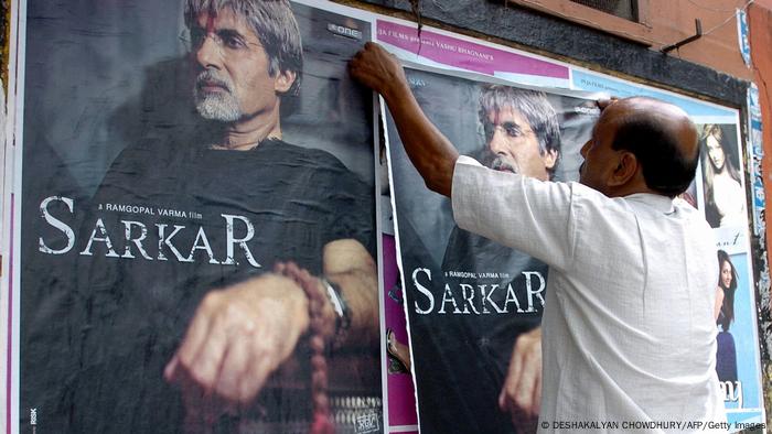 Man hanging up posters for the film Sarkar.