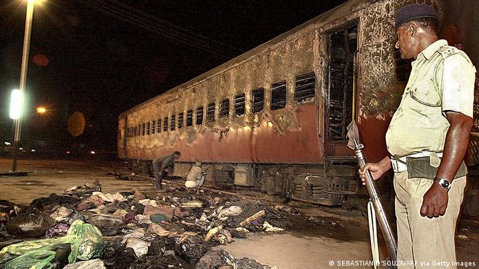 A policeman looks over a burnt coach and belongings of Hindu activists at Godhra station, early February 28, 2002, about 200 kilometers from Ahmadabad.